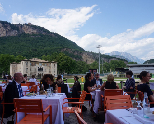 Participants and speakers enjoy lunch together at the MuSe Museum cafe, surrounded by the mountains of Trento, Italy.